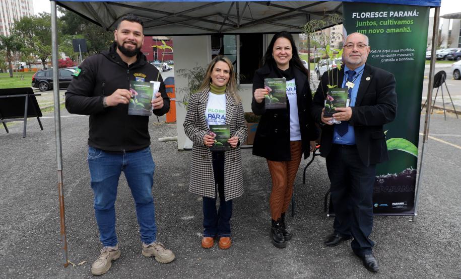 Representantes do IAT posando para foto com civis a frente do banner "Florescer Paraná"