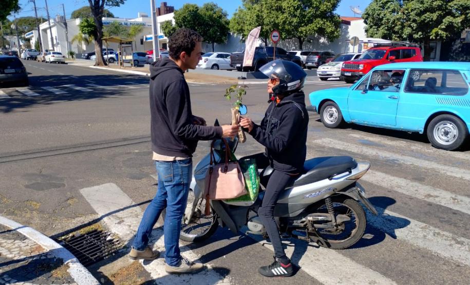 Representante do IAT entregando mudas a um civil em sua motocicleta.