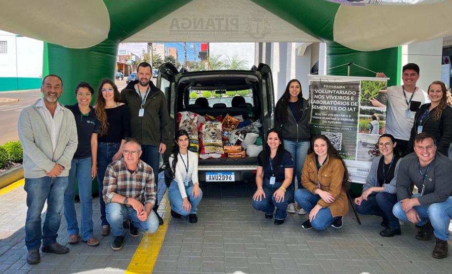 Equipe do IAT de 13 pessoas posando para foto com material do estande ao fundo