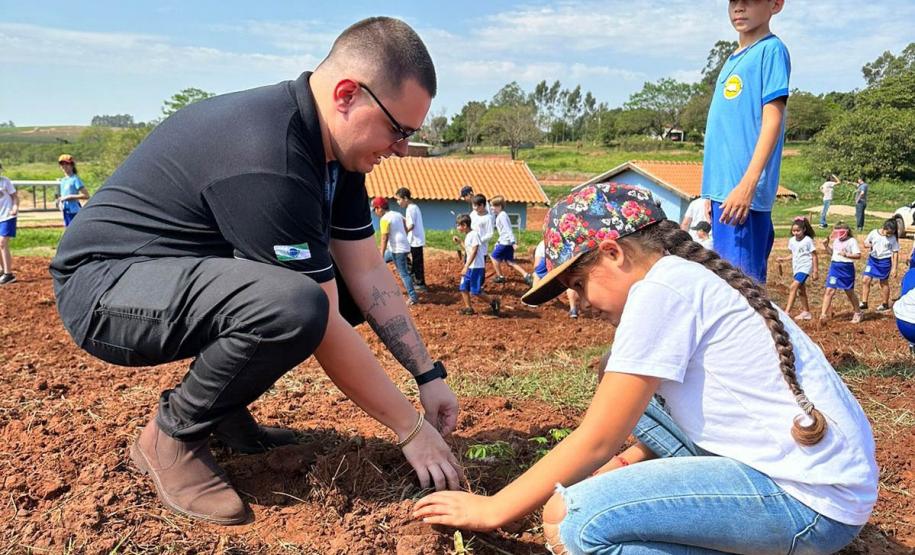 Servidor do IAT ensinando uma criança a plantar uma muda