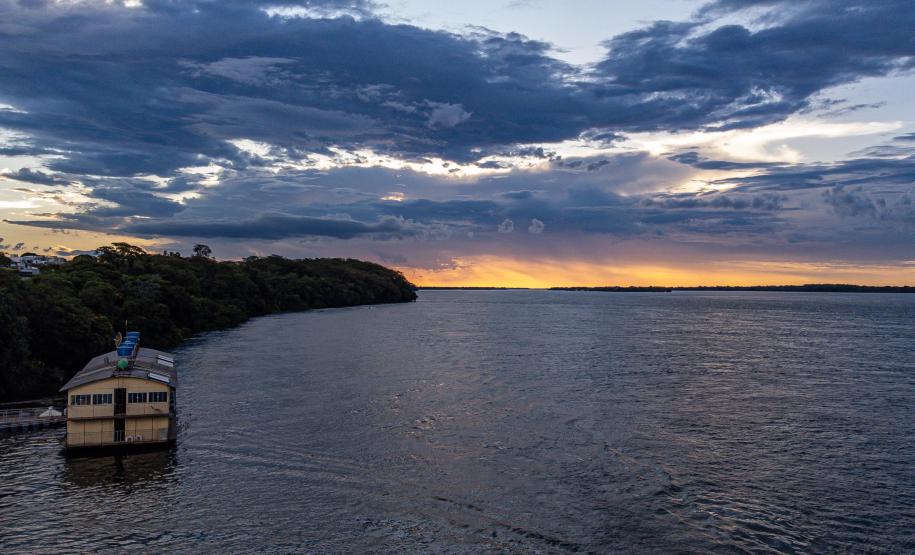 Rio Paraná ao entardecer. Pequena embarcação navegando próxima da margem esquerda.