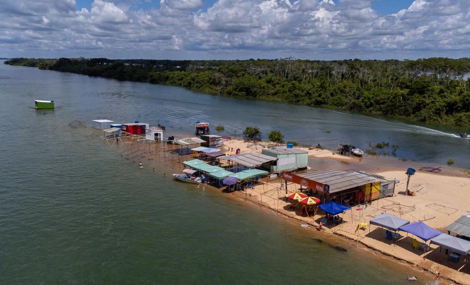 Margem do Rio Paraná com barracas próximas ao rio.
