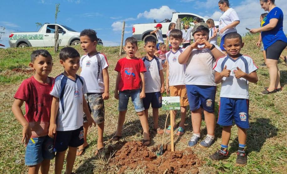Grupo de oito crianças próximas a muda plantada