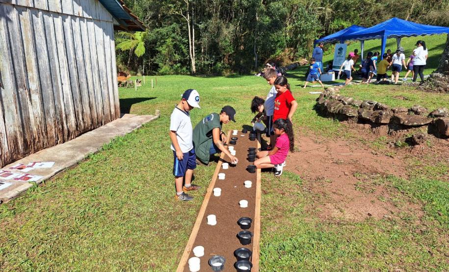 Crianças plantando em sob supervisão de uma técnica do IAT