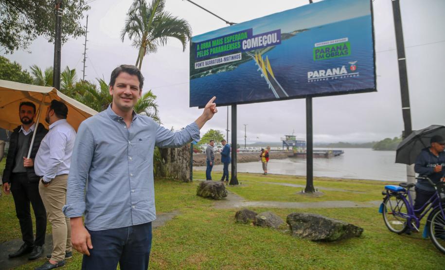 Aliado posando para foto com a placa de inicio das obras ao fundo