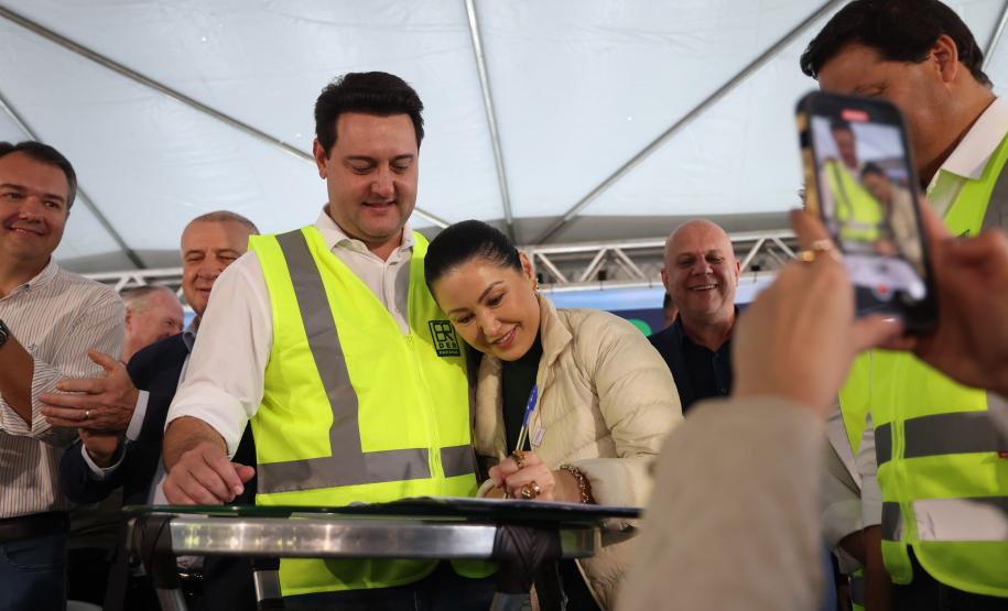 governador vendo integrante do publico assinar um documento