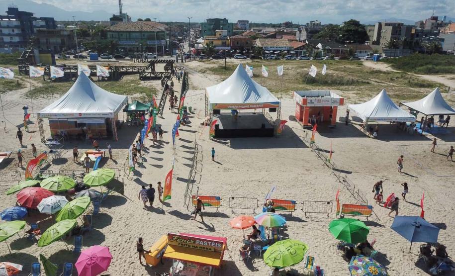 Praia com varios banhistas em torno de barracas e guarda-sois