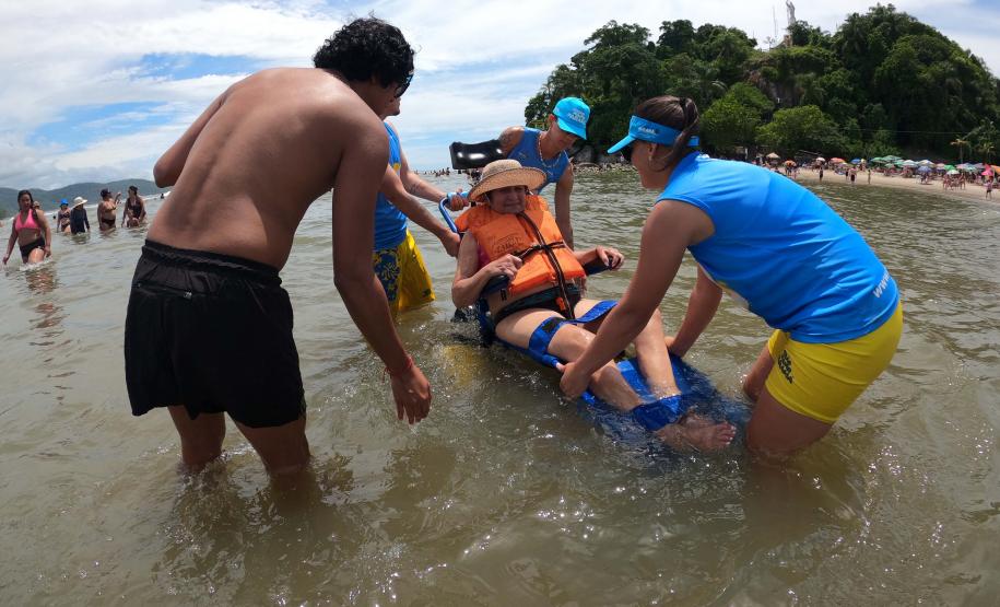Voluntários transportando uma idosa sobre o mar