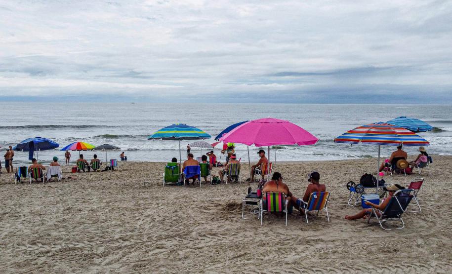 Banhistas apreciando a praia com o mar ao fundo
