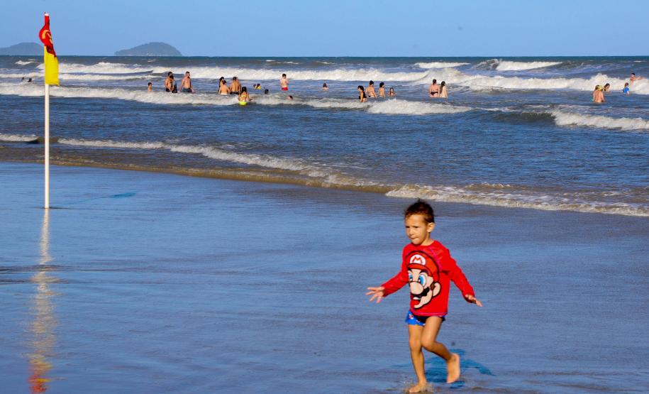 Criança na beira da praia com mar ao fundo