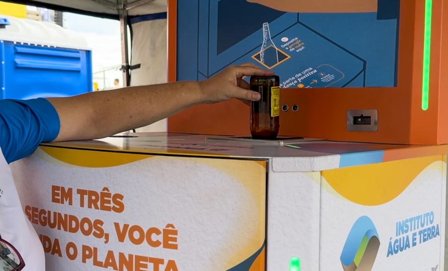 Foto de pessoa depositando garrafa na máquina de reciclagem
