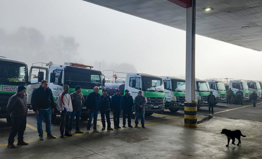 VOLUNTÁRIOS POSANDO COM CAMINHÕES AO FUNDO