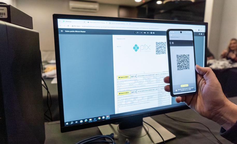 INIDIVÍDUO LENDO UM QR CODE NO COMPUTADOR COM SEU CELULAR