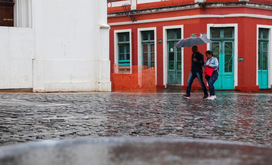 TRANSEUNTES SE PROTEGENDO DA CHUVA NO LARGO DA ORDEM