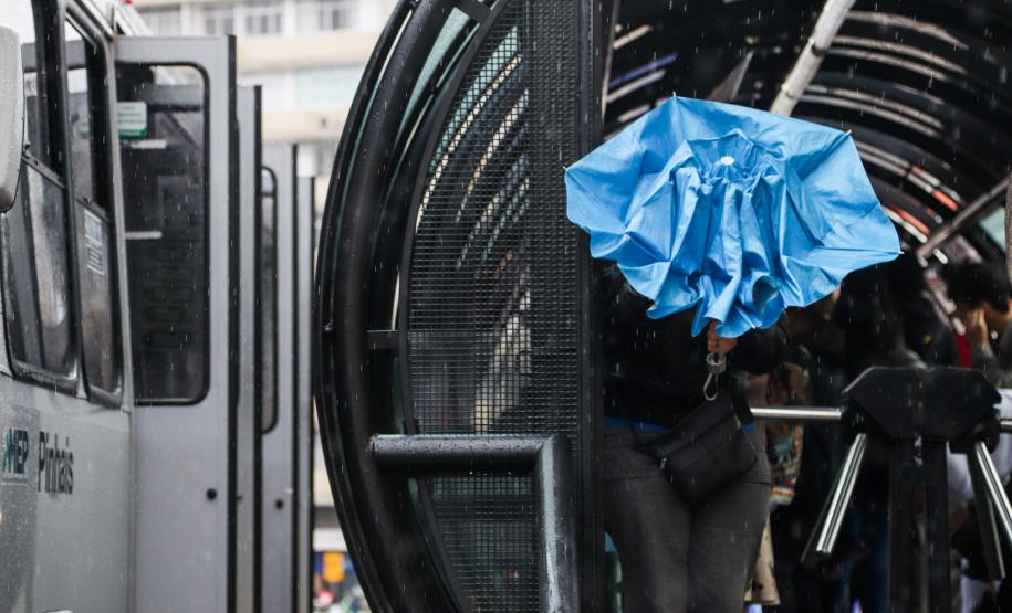 TRANSEUNTE SE PROTEGENDO DA CHUVA FRENTE A ESTAÇÃO TUBO