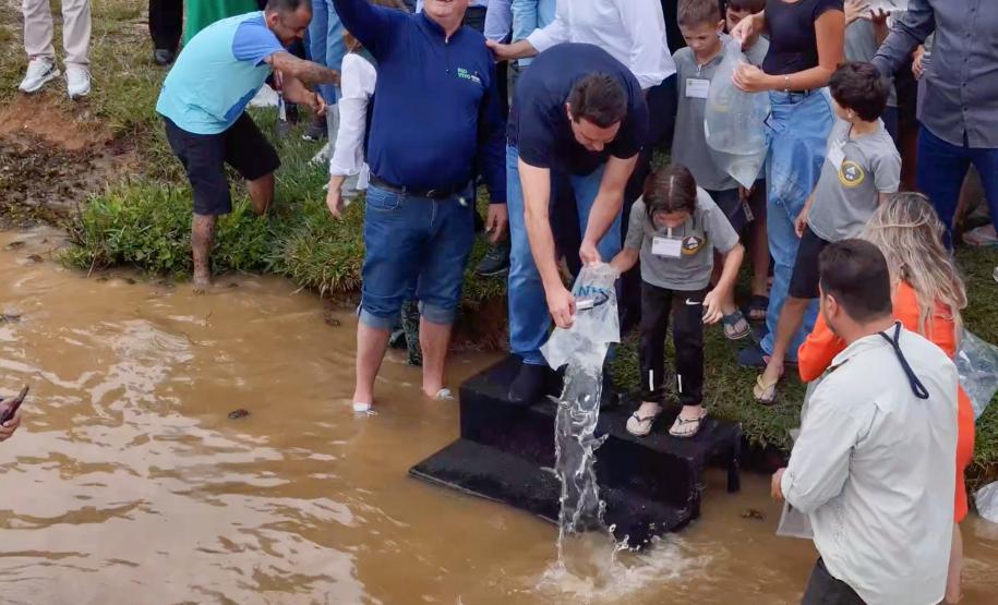 Foto de autoridades e crianças durante soltura de peixes