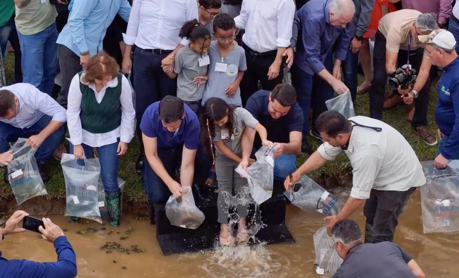 Foto de autoridades e crianças durante soltura de peixes