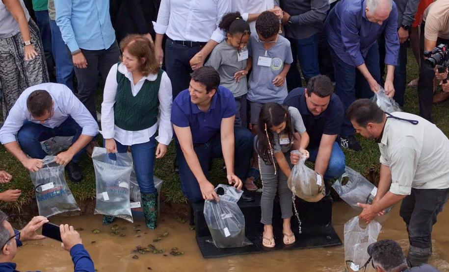 Foto de autoridades e crianças durante soltura de peixes