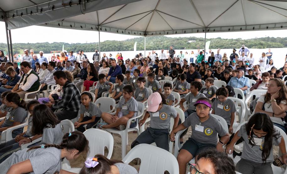 Foto de autoridades e crianças durante soltura de peixes
