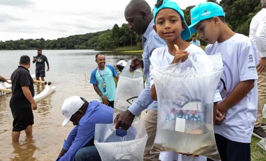Foto de autoridades e crianças durante soltura de peixes