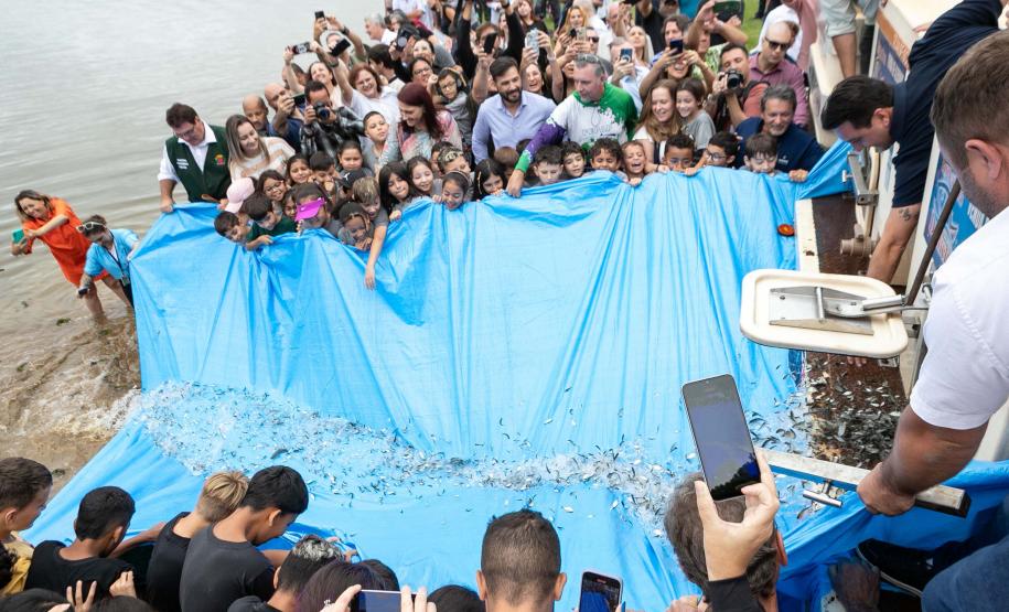 Foto de autoridades e crianças durante soltura de peixes